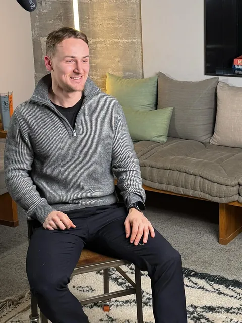 Marvin Gräber, Gründer der Zukunftswerkstatt, sitzt in einem hellen Raum und lächelt.