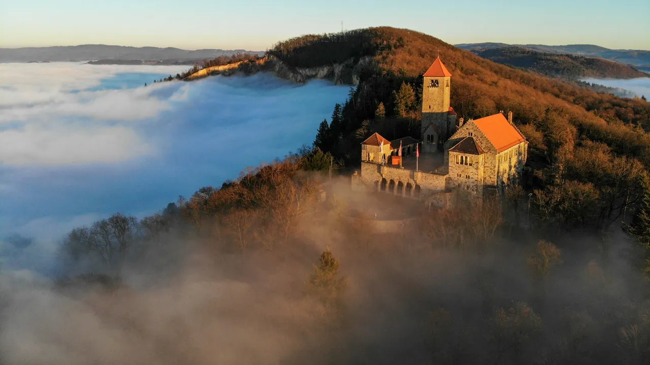 Die Wachenburg über Weinheim im Morgenlicht, das Tal darunter im Nebel.